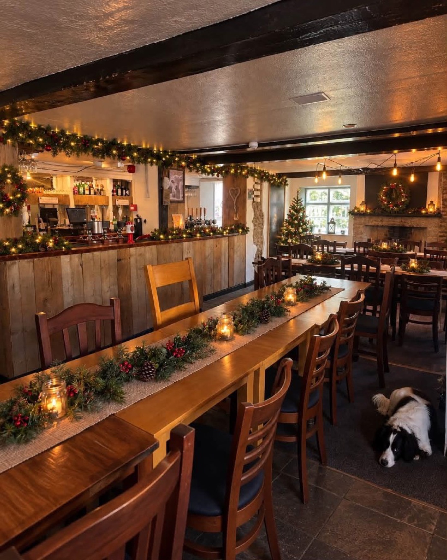 The Red Cow dining room decorated for Christmas with garlands, candles and fairy lights